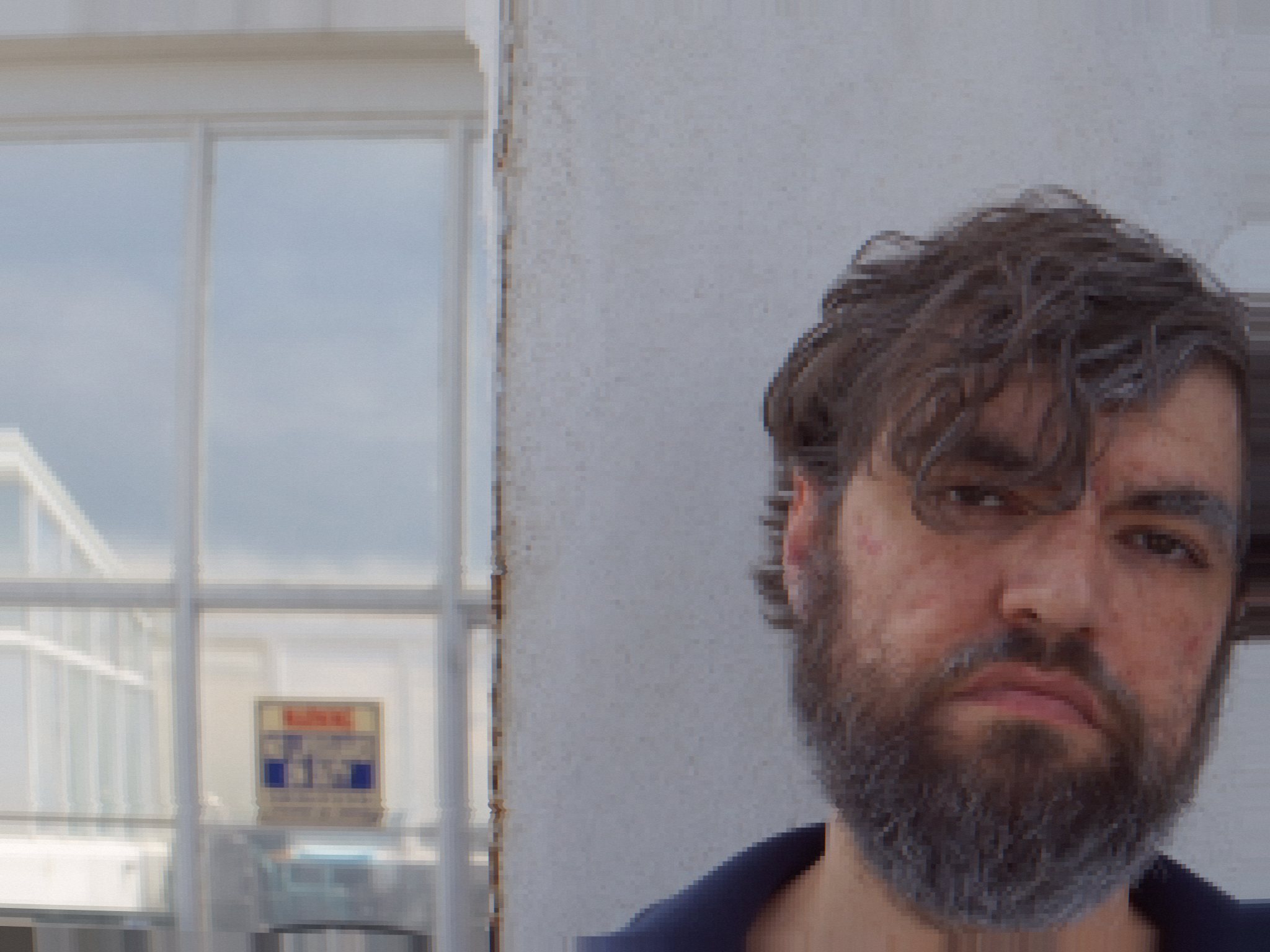 Frank Ashman stares into the camera, unimpressed, against a white wall